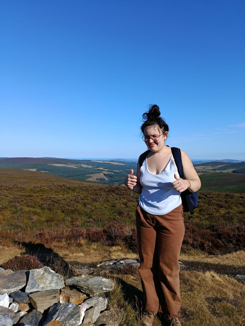 Ella with two thumbs up among heather