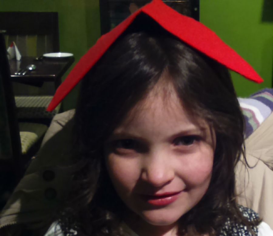 Young Ella with a red paper hat on her head